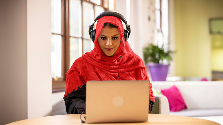 A woman sits in front of a computer and takes the IELTS.